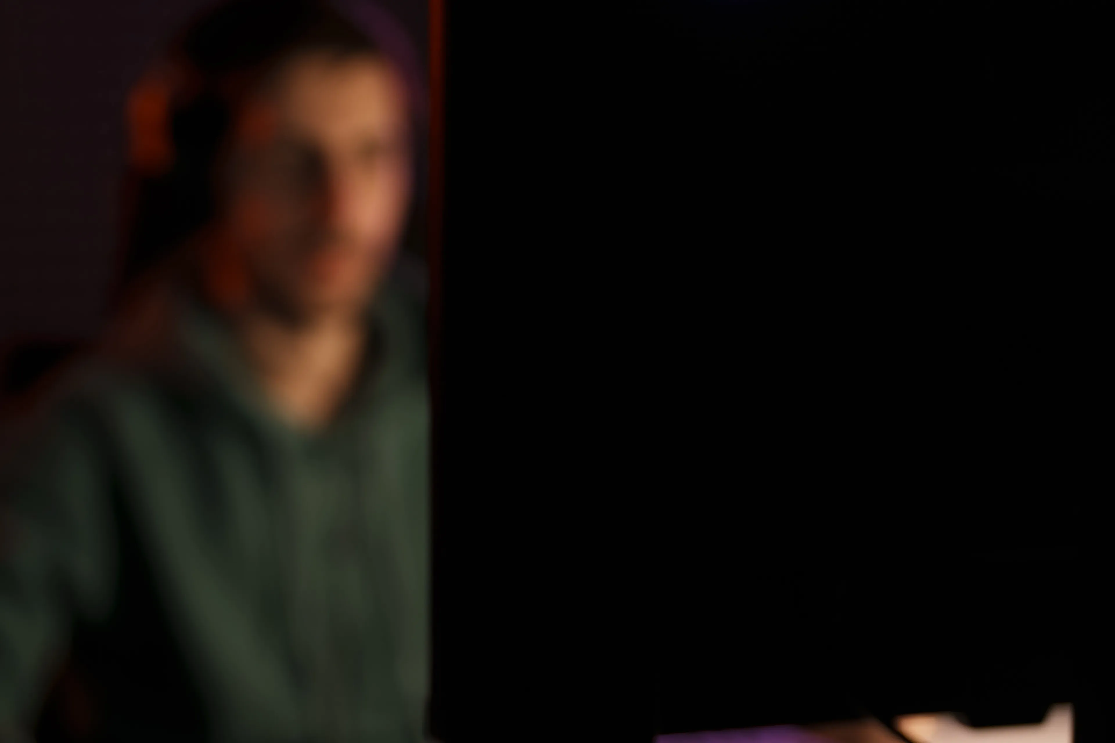 Ein person som sit i eit mørkt rom foran en PC