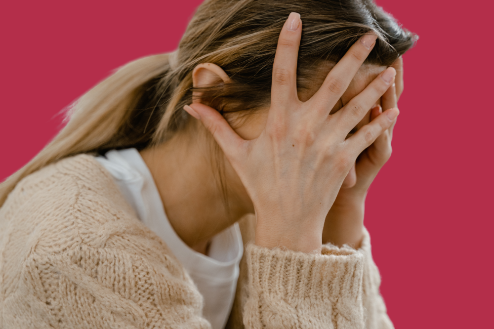 Ei kvinne som dekker ansiktet med hendene.