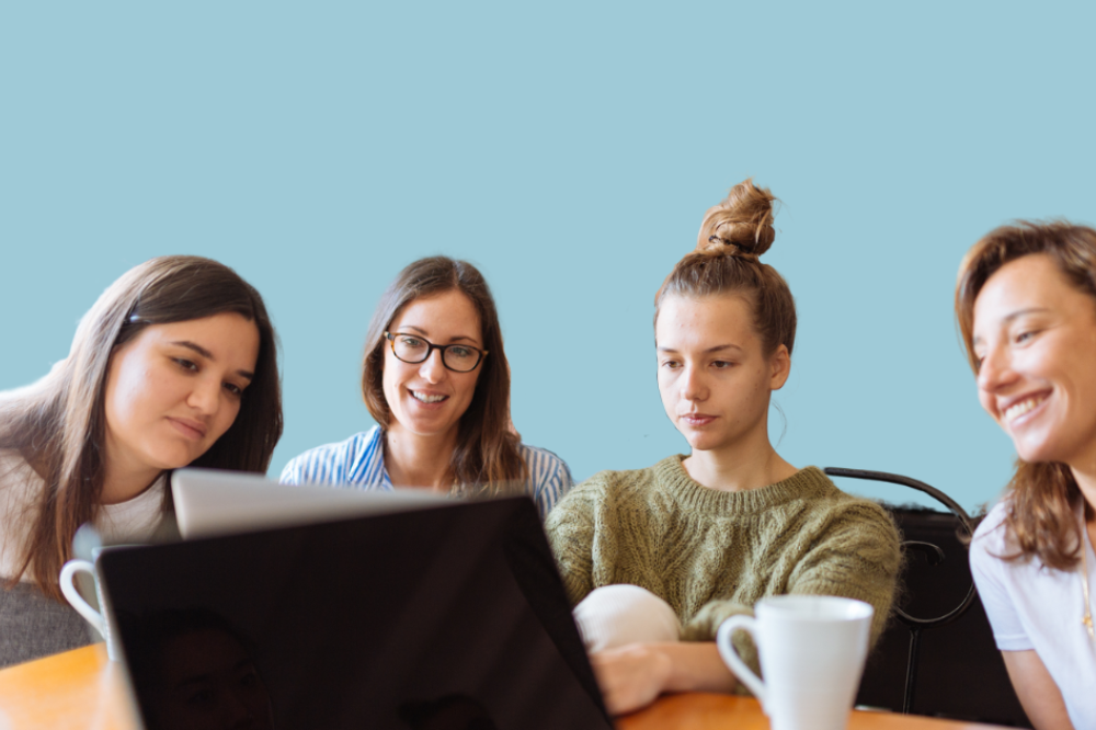 En gruppe mennesker som sitter ved et bord med en bærbar datamaskin.