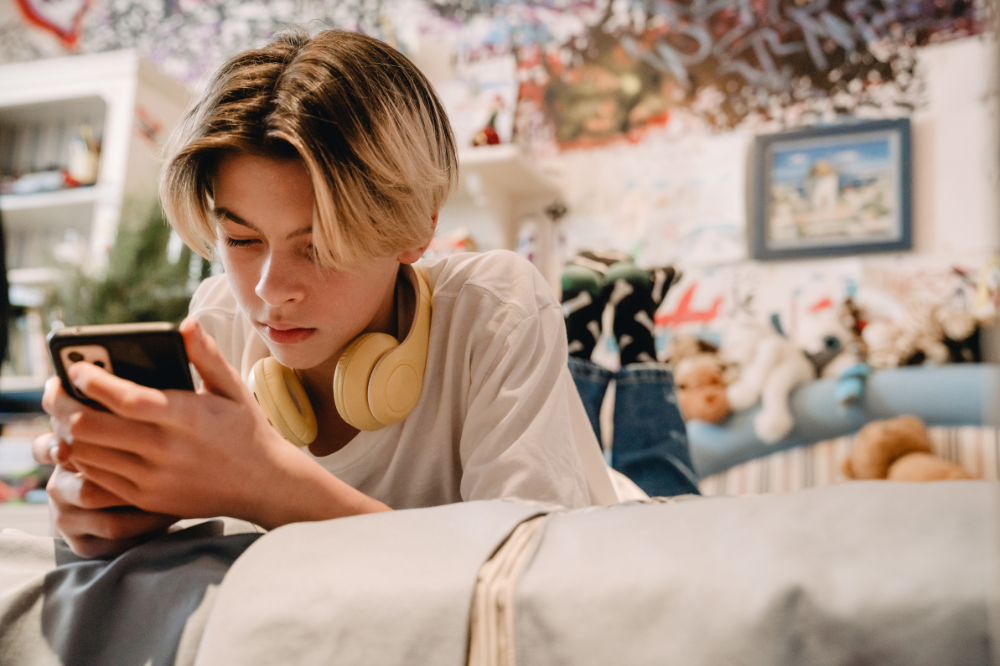 Ein ung gut sit i ein sofa og ser på telefonen sin.