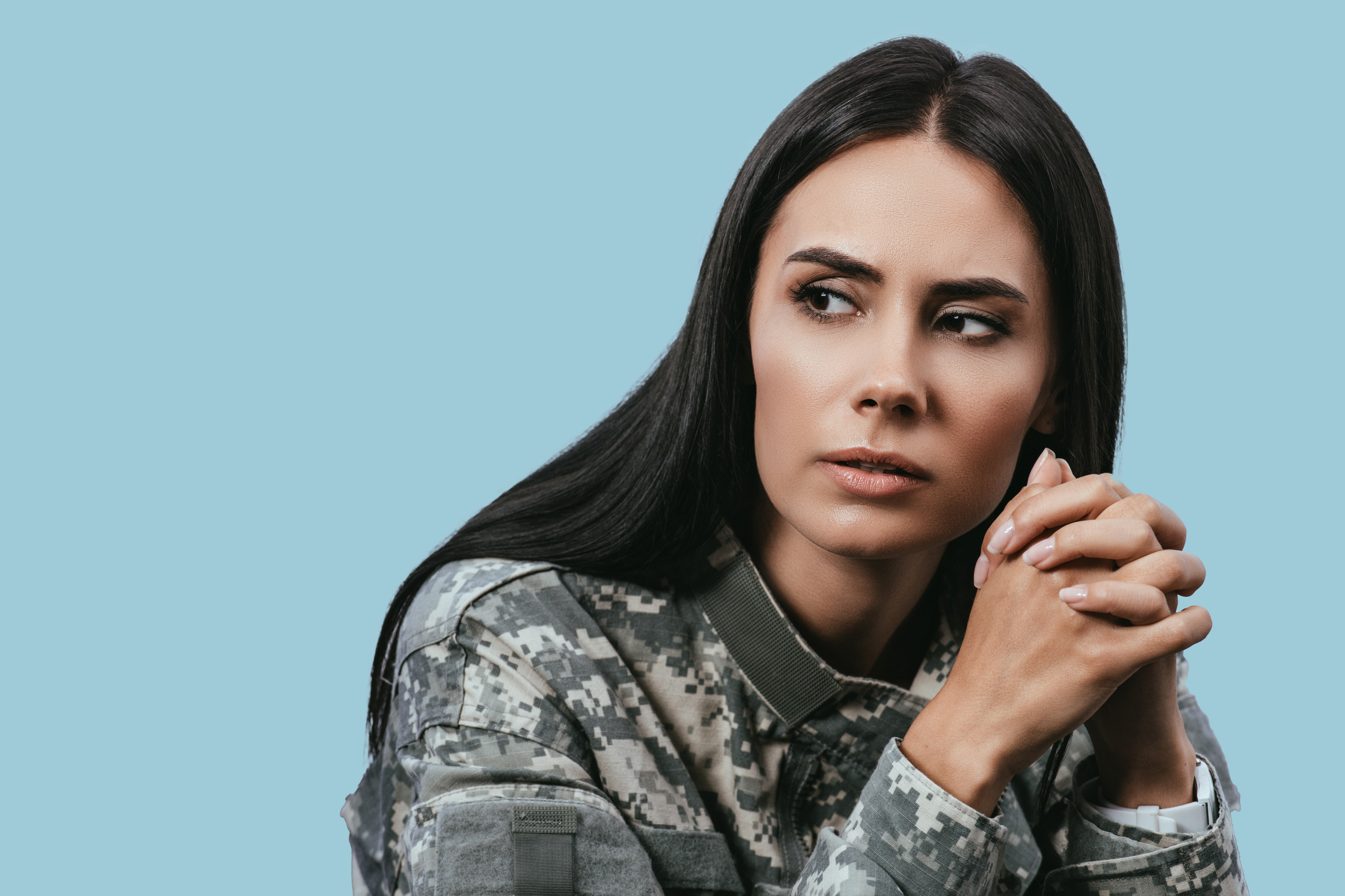 Ei kvinne i militæruniform sit framfor kamera og ser til sida.