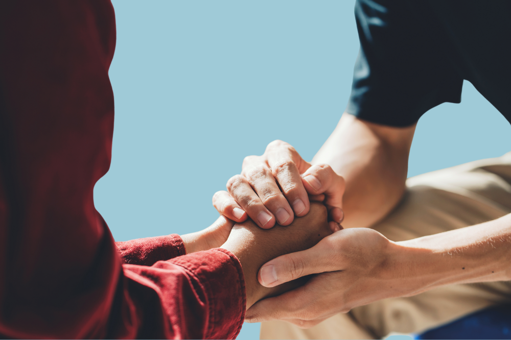 Eit nærbilete av to personar som held kvarandre sine hender.