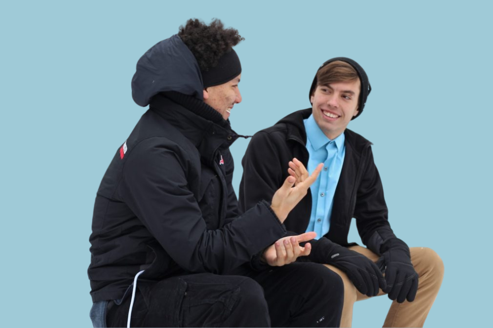 Eit par menn som sit på ein benk og snakkar saman.