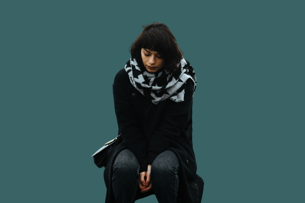 Ei kvinne som sit aleine på ein benk.