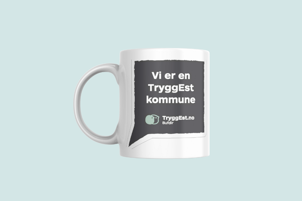 Et hvitt krus med reklame for Tryggest