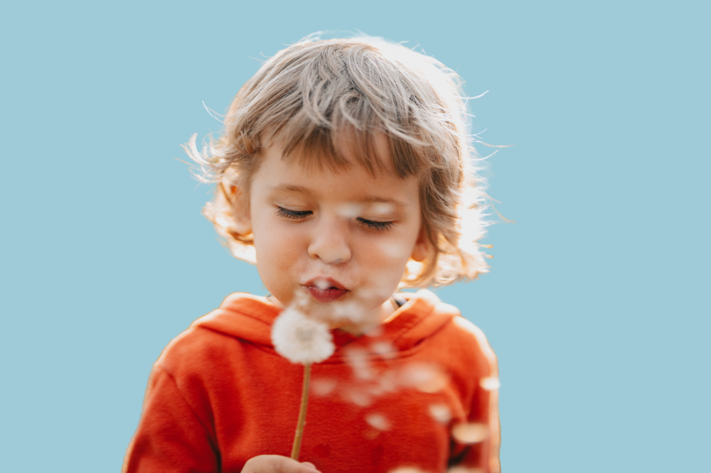 Eit barn som blåser løvetann