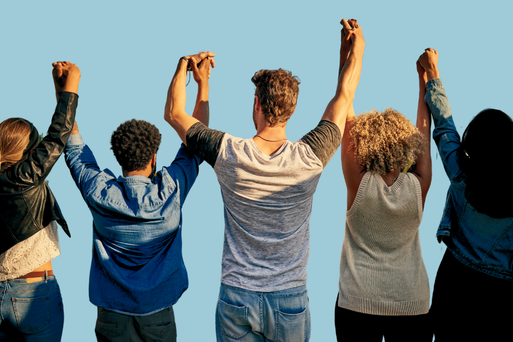 Ei gruppe menneske som holder hender og rekker dei opp i lufta.