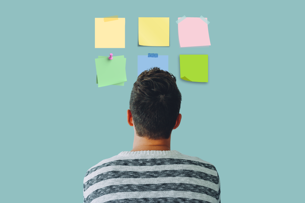 Ein mann som ser på ein vegg med klistrelappar på