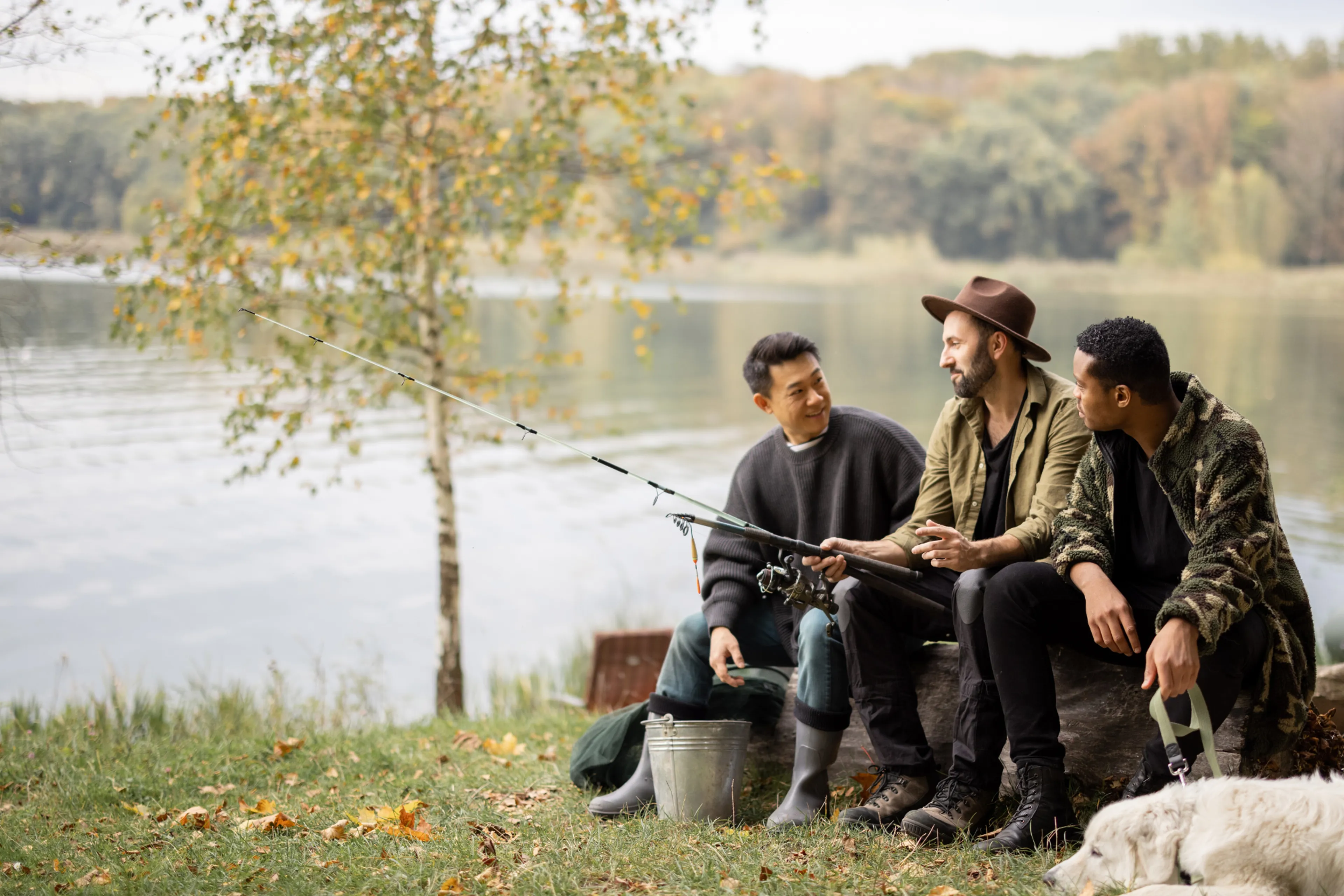 Ei gruppe menn og ein hund ved ein innsjø. Dei har fiskeutstyr.