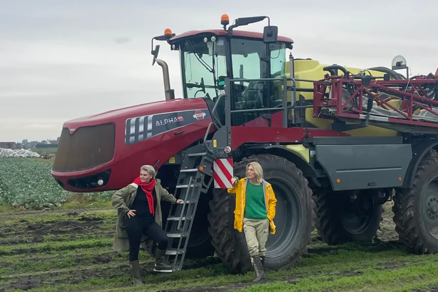 Randi Mossefinn og Linda Thomassen står foran ein traktor på eit jorde.